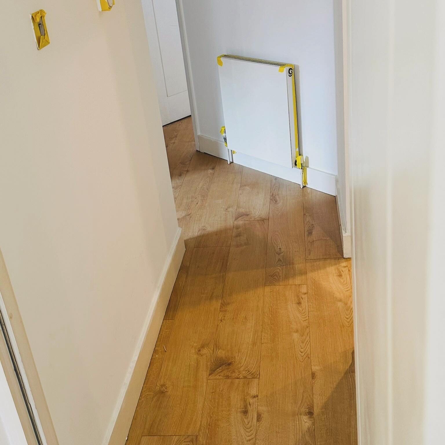 Warm engineered oak flooring in a white hallway