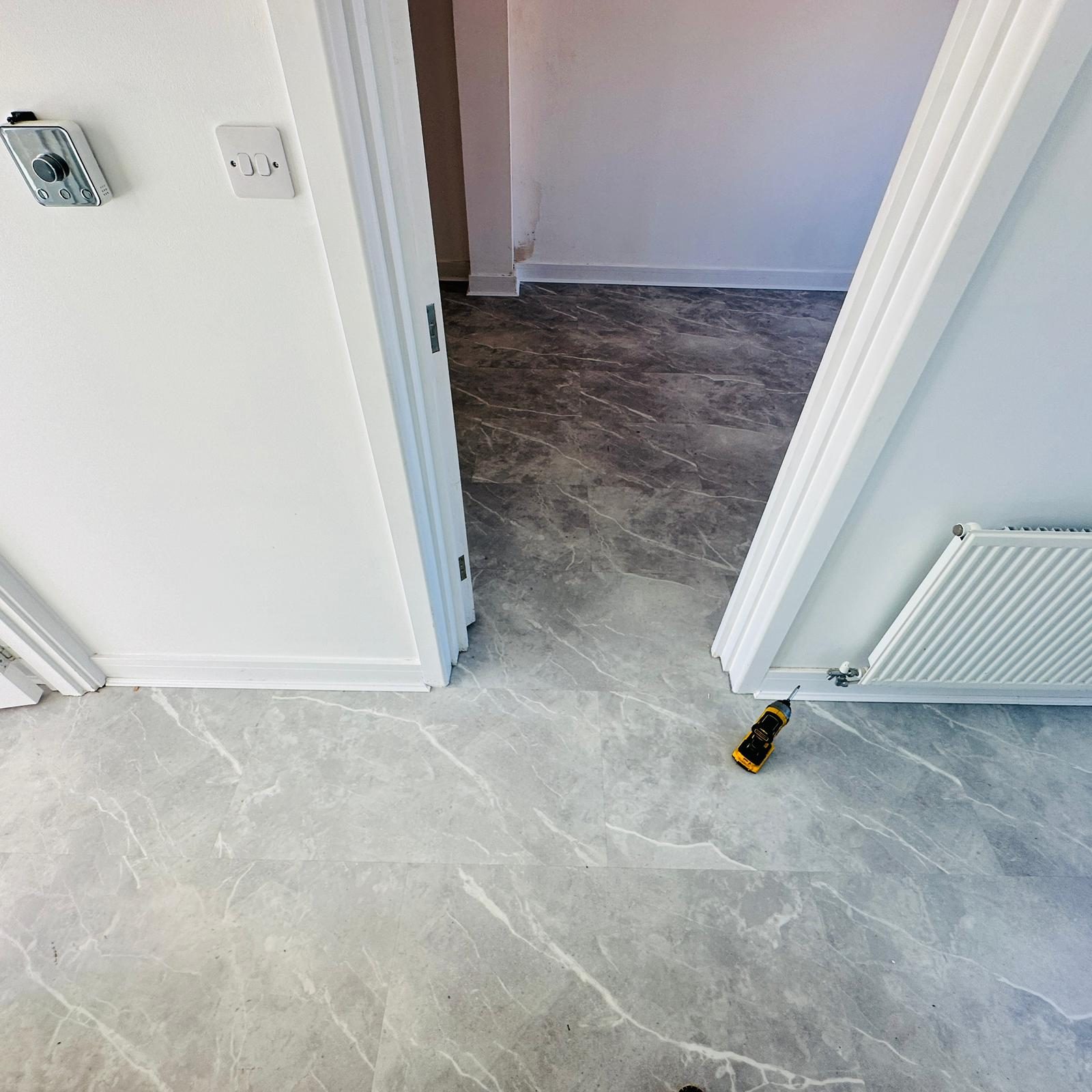 Grey marble-effect LVT tiles being installed in a London home
