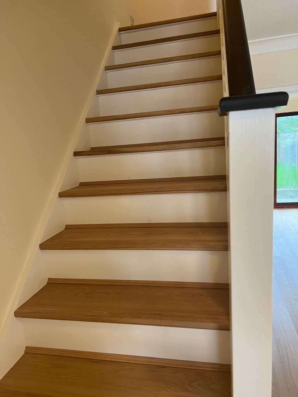 Natural oak engineered wood staircase with white risers and dark handrail