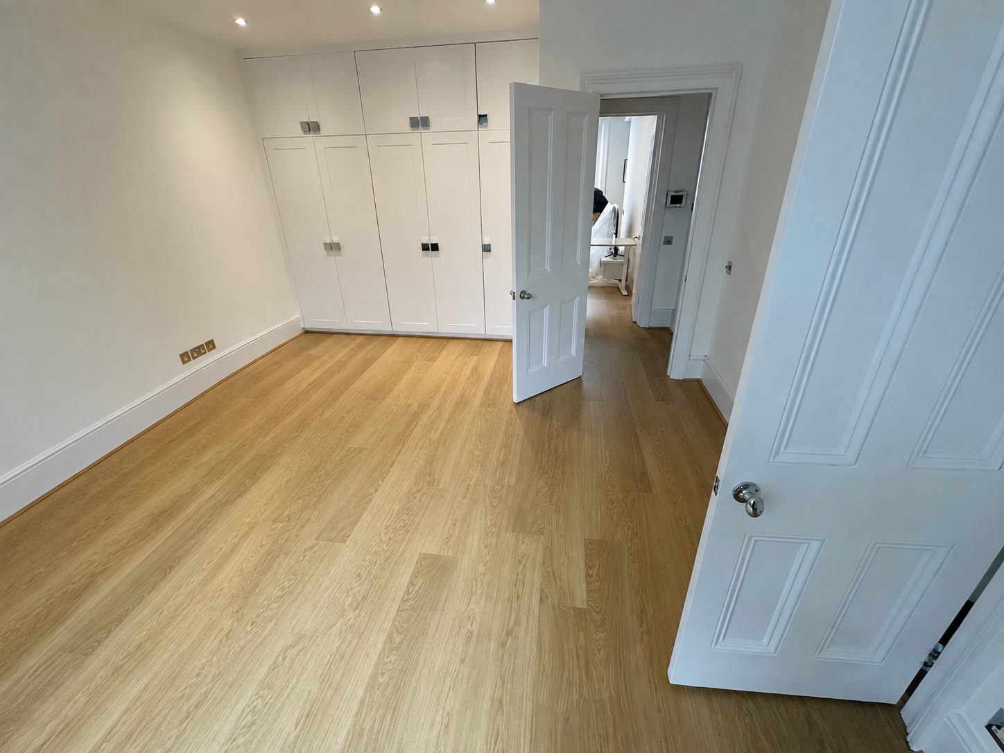 Natural rustic oak engineered flooring in a bedroom with fitted wardrobes