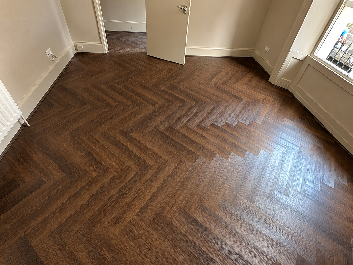 Dark brown herringbone flooring fitted throughout a spacious London room
