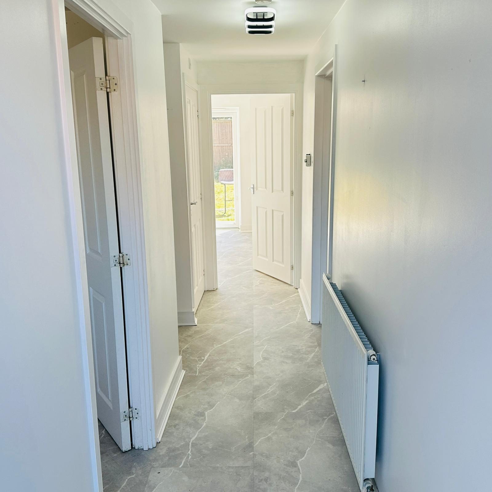 Marble-effect LVT flooring in a bright hallway leading to a glass door