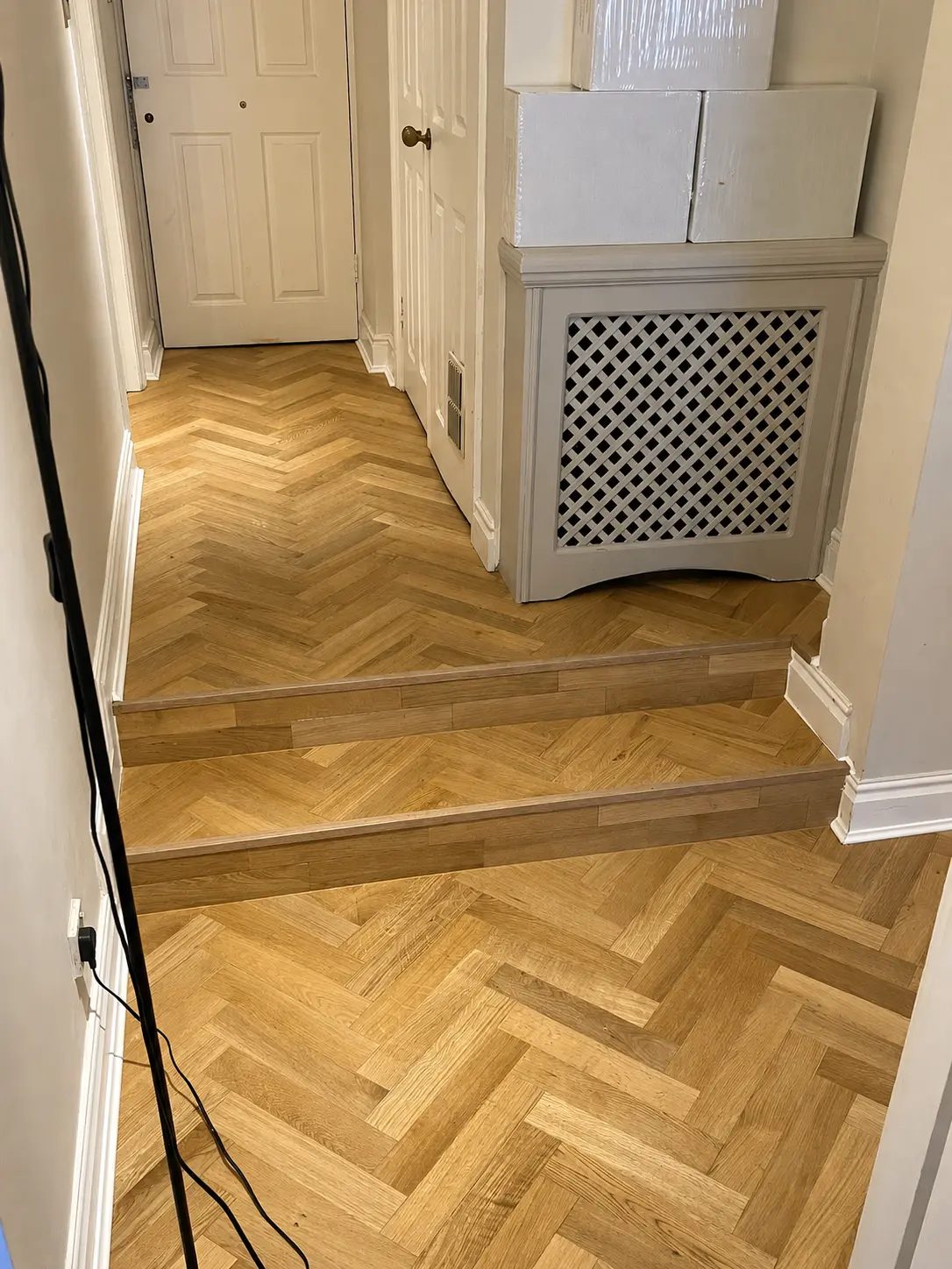 Herringbone flooring meeting timber-treaded steps in a hallway, Baker Street